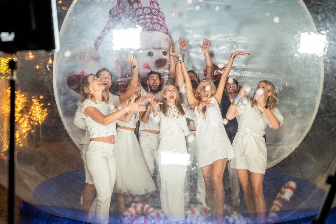 Guests celebrating inside a giant snow globe photo booth