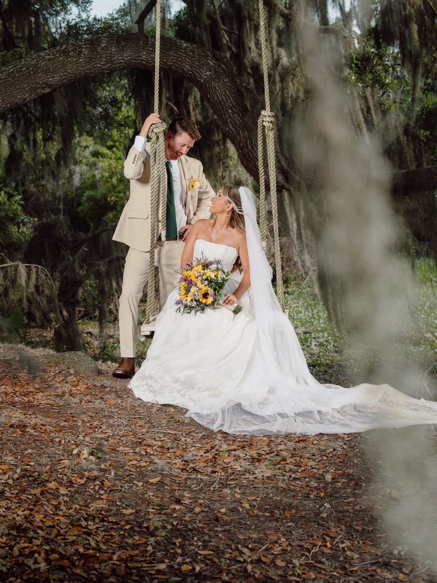 Bride and groom on a rope swing under oak trees